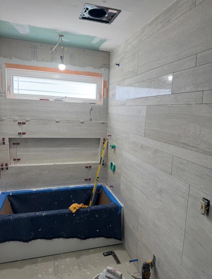 Bathroom mid-remodel with new wall tile going up around the tub