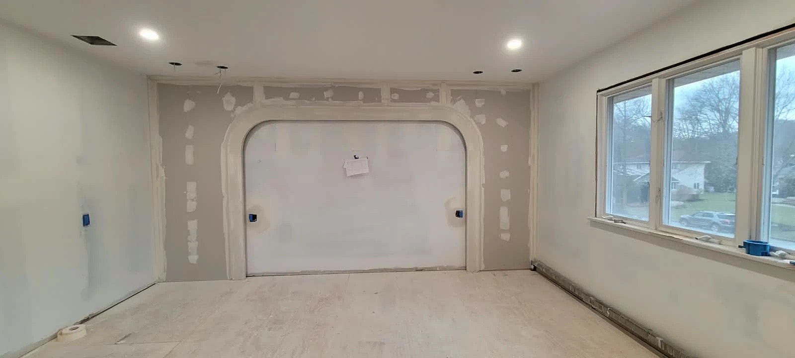 Bedroom with new drywall, a curved feature arch and recessed lighting before paint
