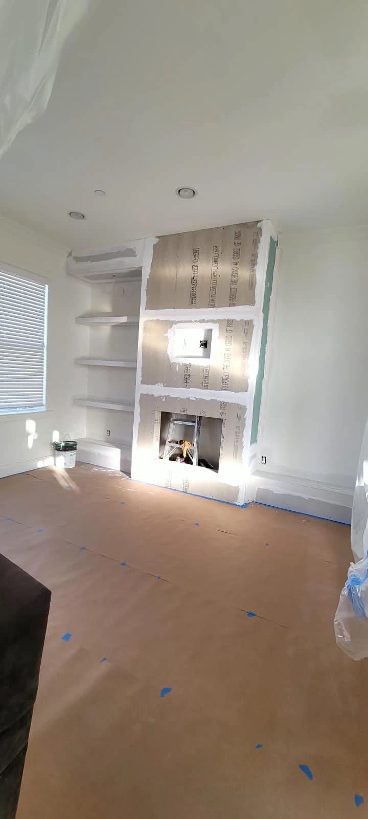 Fireplace wall framed and drywalled with built-in shelf niches before finishing