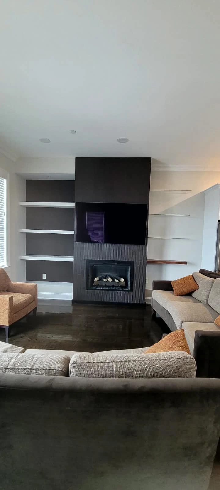 Finished fireplace wall with a custom decorative finish, recessed TV and floating shelves